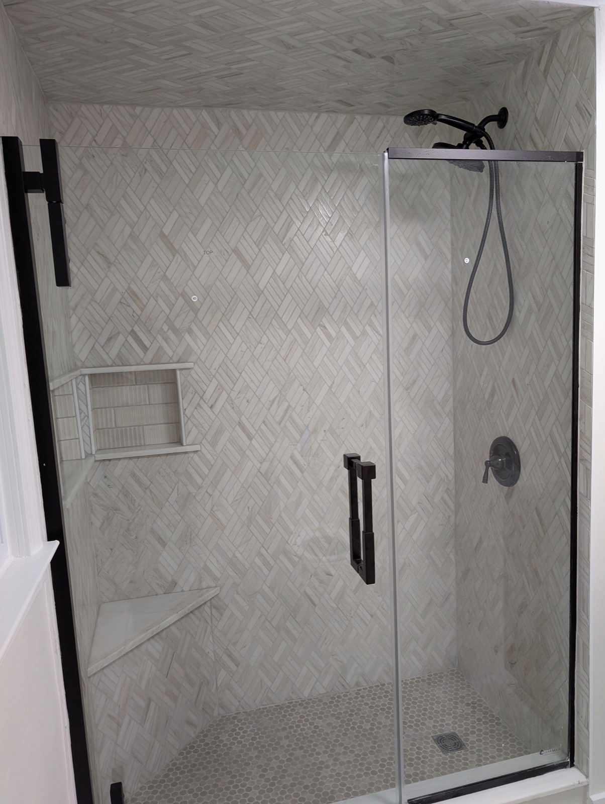 Finished bathroom remodel with marble-slab shower, frameless glass enclosure, and floating oak vanity