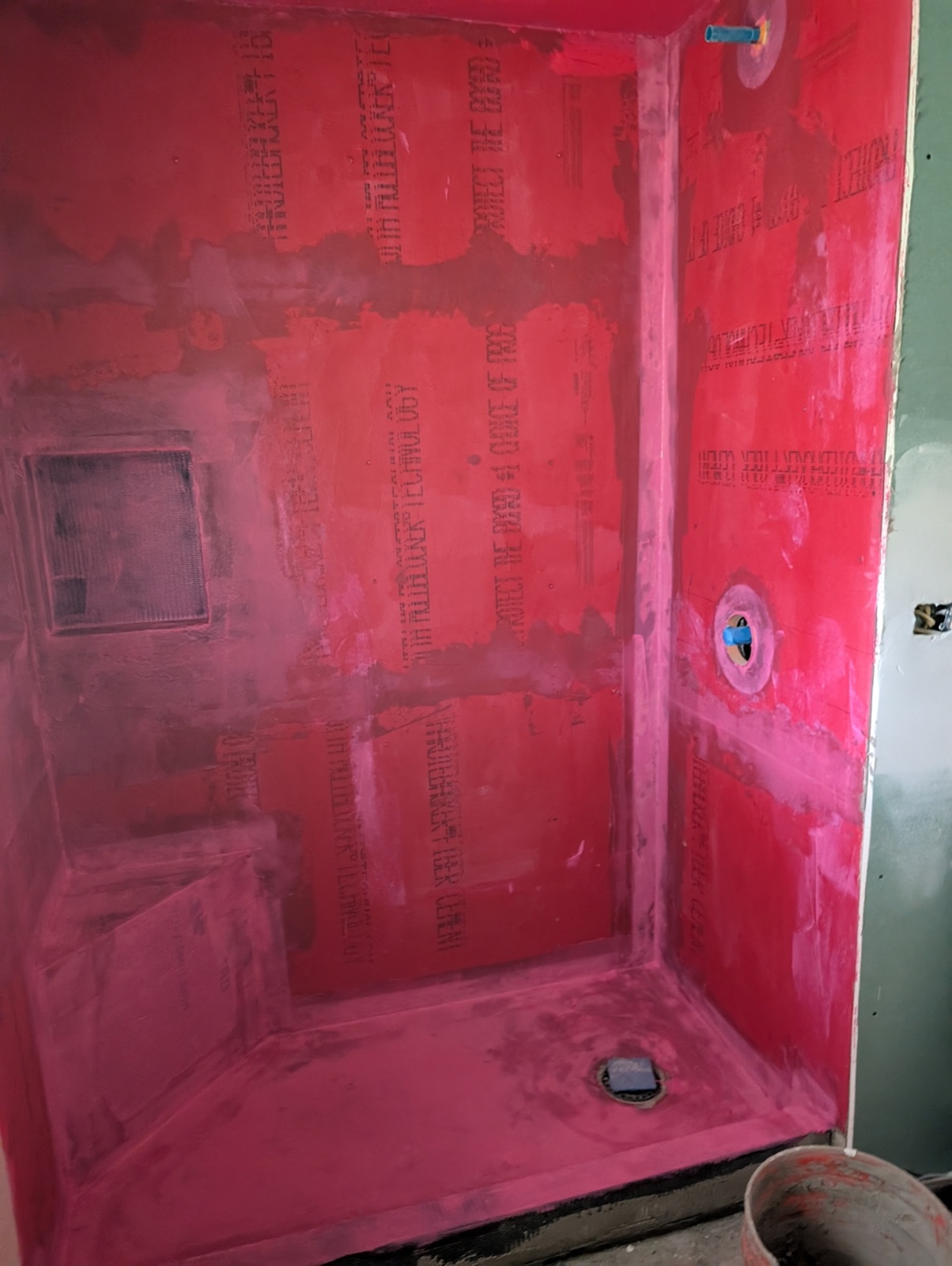 Shower walls framed and waterproofed with red membrane before tile